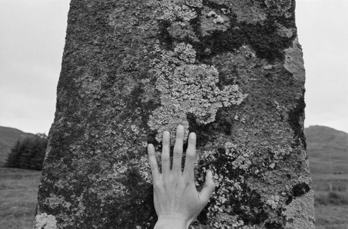 a hand placed on a standing stone