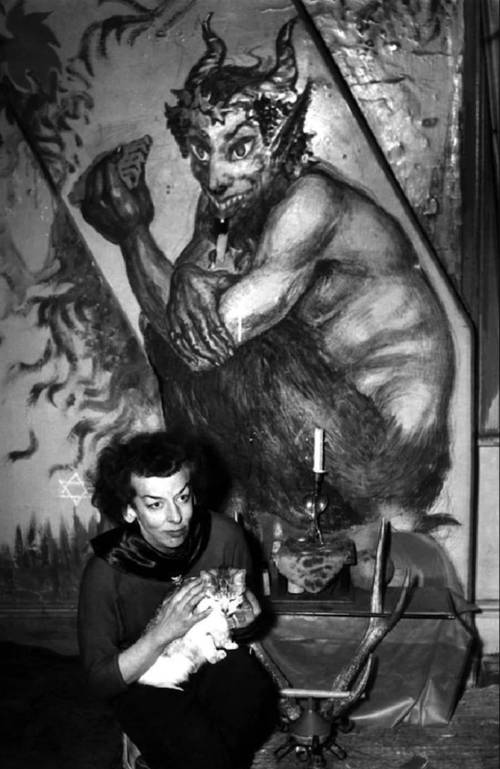 a woman sits in front of nightmarish painting of a devil